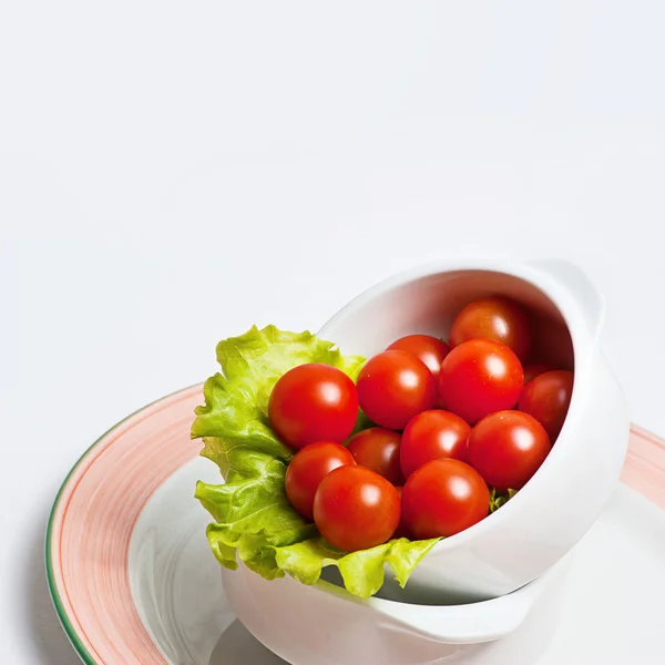 Tomates fraîches avec feuilles de salade dans un bol — Photo