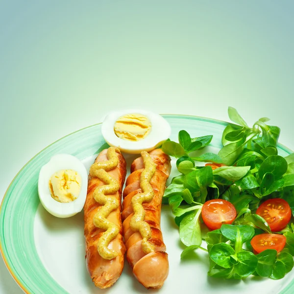 Sausages on the grill with mustard, egg, salad and tomatoes — Stock Photo, Image