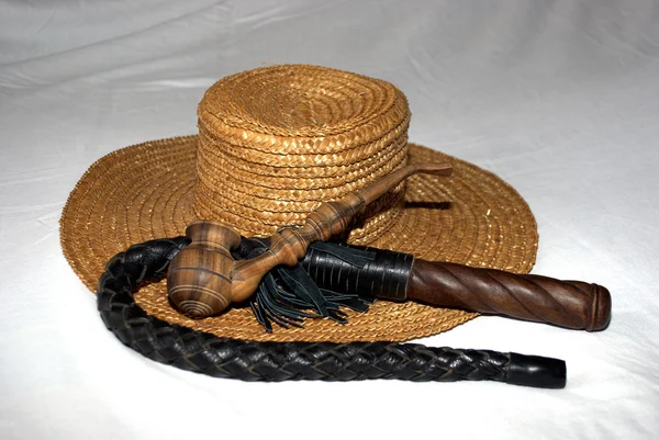 Słomkowy kapelusz z batem i drewniane fajka — Zdjęcie stockowe