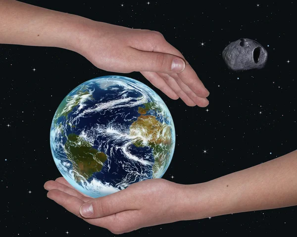 Hands covering the world from a meteorite — Stock Photo, Image