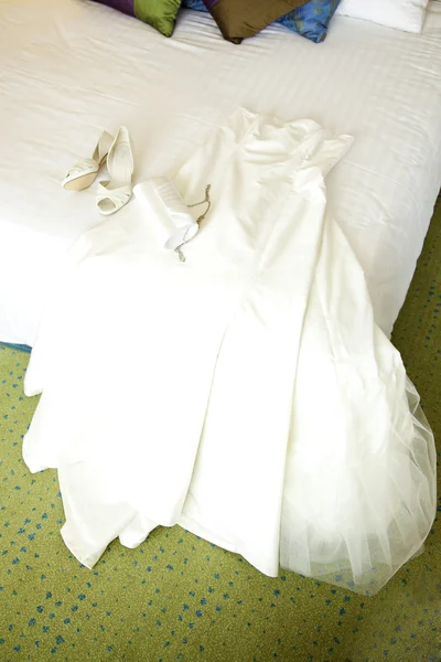 Wedding gown, shoes and bag on the bed — Stock Photo, Image