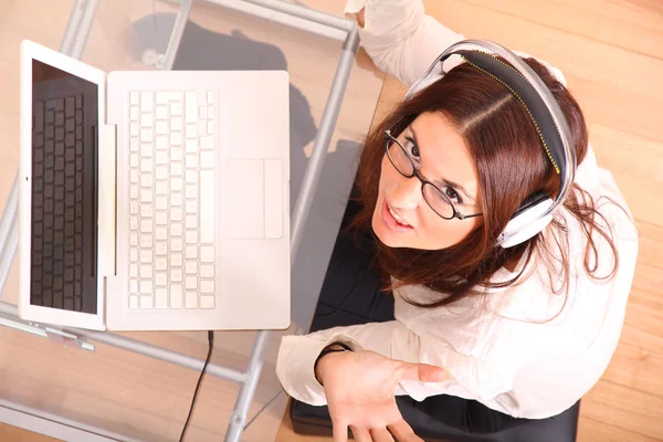 Mujer riendo con un ordenador portátil y auriculares —  Fotos de Stock