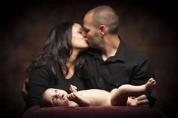 Mixte course couple baiser tandis que bébé pose sur oreiller — Photo