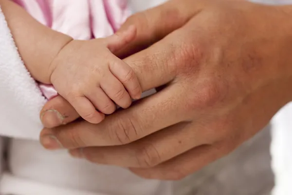 Dziecko dziewczynka ręki trzymającej szorstki palec taty — Zdjęcie stockowe
