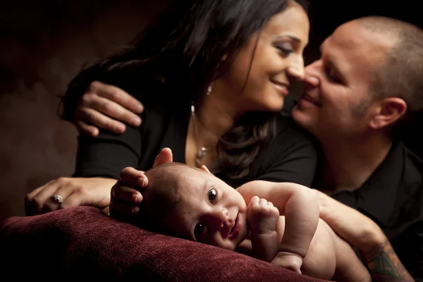 Mischlingspaar schaut liebevoll zu, während Baby auf Kissen liegt — Stockfoto