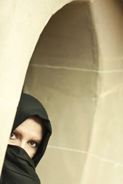 Προσεκτική ισλαμική γυναίκα στο παραθύρου που φοράει την μπούρκα ή niqab — Φωτογραφία Αρχείου