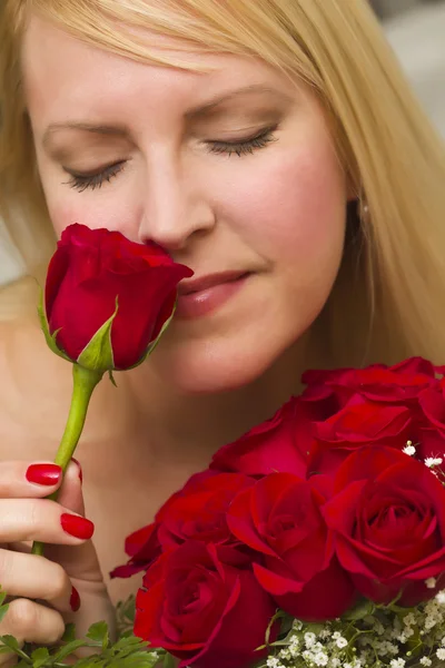 Γυναίκα μυρίζοντας μια δέσμη των κόκκινων τριαντάφυλλων — Φωτογραφία Αρχείου