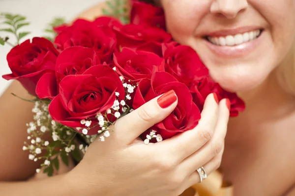 Femme souriante tenant une grappe de roses rouges — Photo