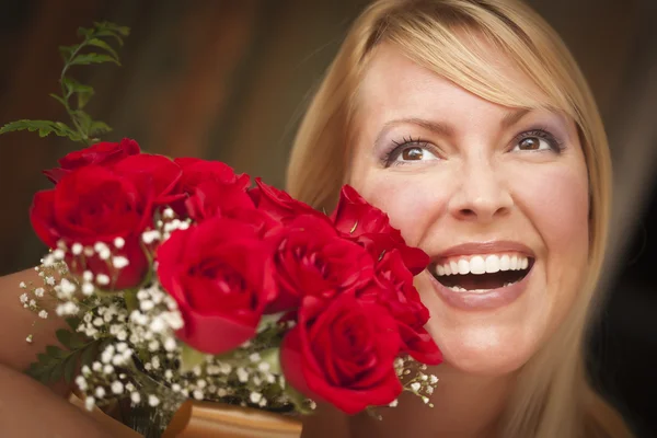 Χαμογελώντας ξανθιά γυναίκα με κόκκινα τριαντάφυλλα — Φωτογραφία Αρχείου