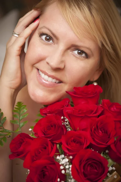 Lächelnde blonde Frau mit roten Rosen — Stockfoto