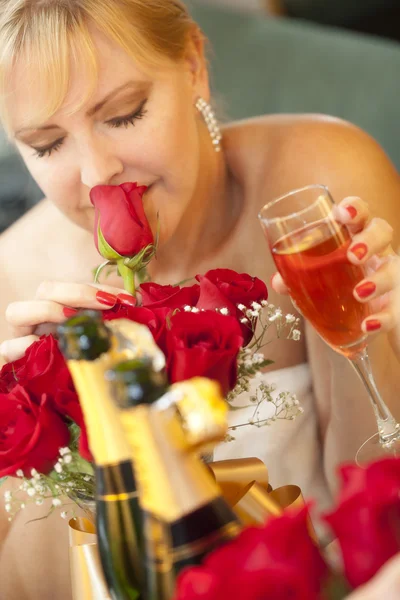 Mujer rubia huele rosas en el espejo cerca de champán — Foto de Stock