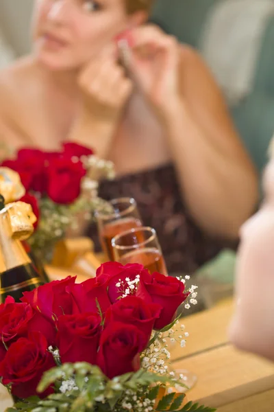 Mulher loira aplica maquiagem no espelho perto de champanhe e rosas — Fotografia de Stock