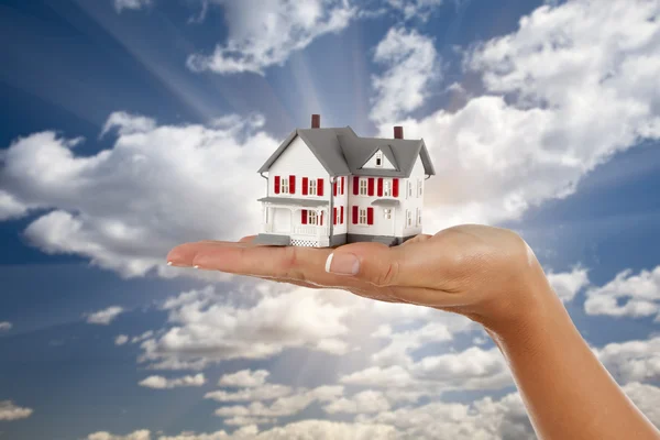 Модельный дом в женской руке на фоне неба — стоковое фото