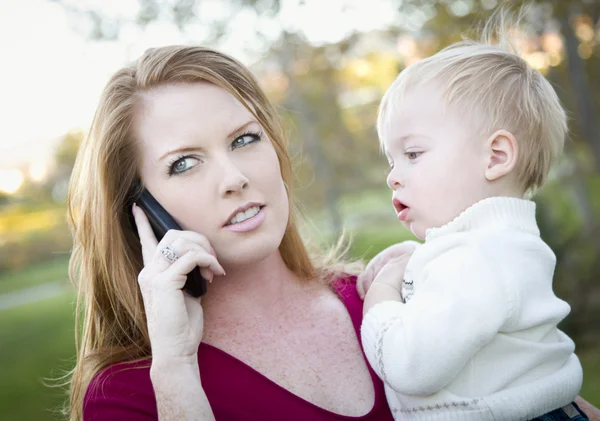 Ελκυστική γυναίκα χρησιμοποιώντας κινητό τηλέφωνο με το παιδί — Φωτογραφία Αρχείου