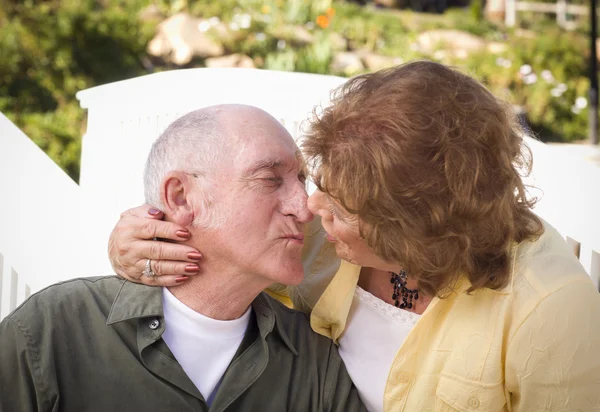 Поцелуи пожилой пары в парке — стоковое фото
