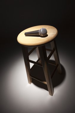 Microphone Laying on Wooden Stool Under Spotlight clipart