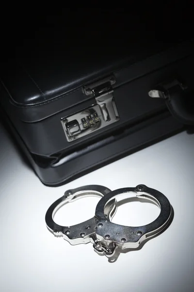 Пара наручників і портфеля під прожектором — стокове фото