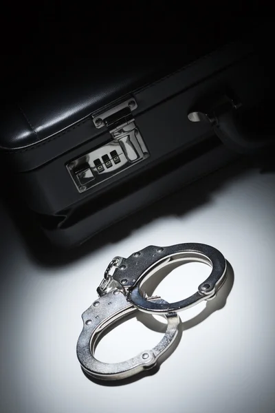Paar Handschellen und Aktentasche im Scheinwerferlicht — Stockfoto