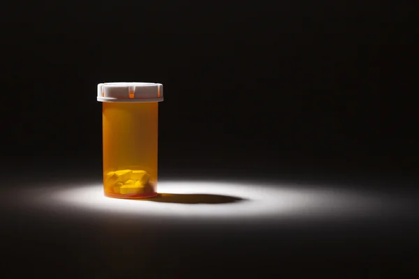 Garrafa de remédio e comprimidos sob luz do ponto — Fotografia de Stock