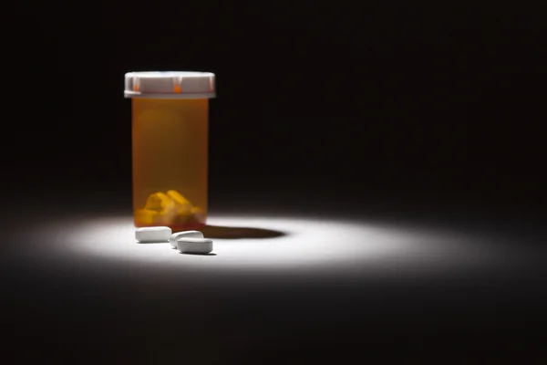 Ilaç şişesi ve hap spot ışığı altında — Stok fotoğraf