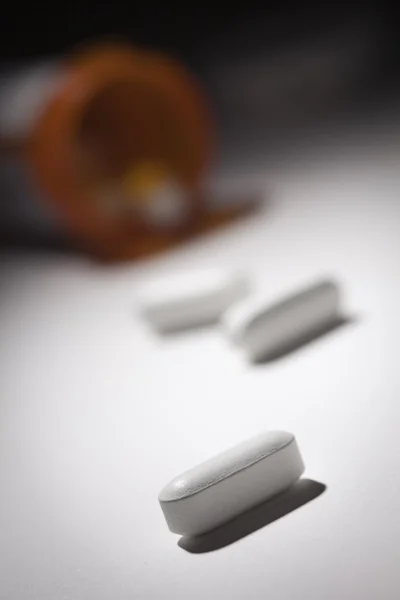 Garrafa de remédio e comprimidos sob luz do ponto — Fotografia de Stock