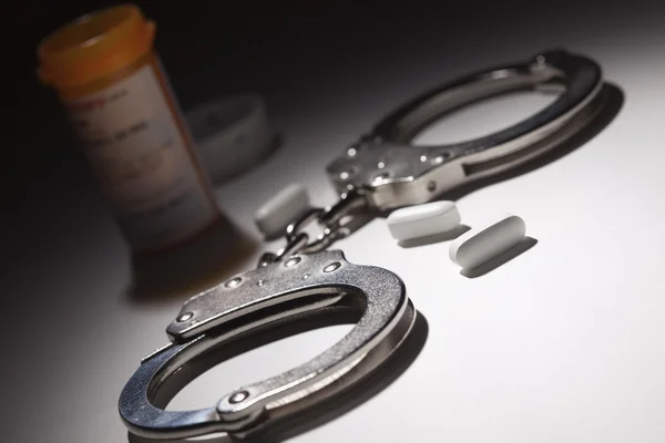 Handcuffs, Medicine Bottle and Pills Under Spot Light — Stock Photo, Image