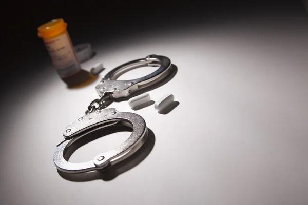 Handcuffs, Medicine Bottle and Pills Under Spot Light — Stock Photo, Image
