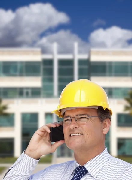 Подрядчик в каскаде говорит по телефону перед зданием — стоковое фото