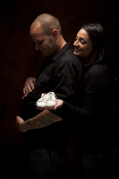 Mixed Race Couple Holding New White Baby Shoes on Black — Stock Photo, Image