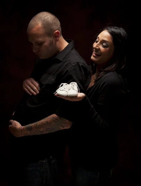 Pareja de raza mixta sosteniendo nuevos zapatos de bebé blancos en negro — Foto de Stock