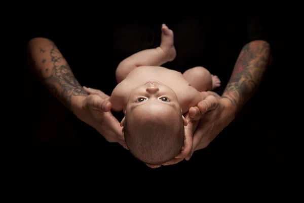 Les mains du père et de la mère tiennent le nouveau-né sur le noir — Photo