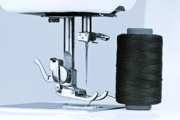 Синяя тонированная швейная машина и катушка с ниткой — стоковое фото