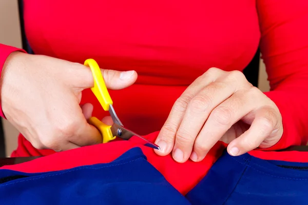 Mãos cortando um pedaço de tecido — Fotografia de Stock
