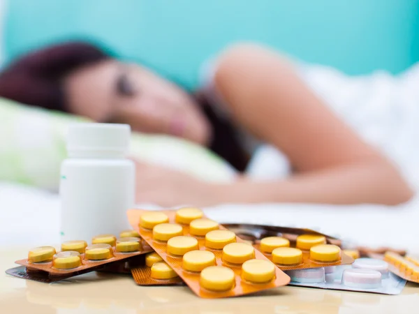 Mulher doente na cama e pílulas de seu tratamento médico — Fotografia de Stock