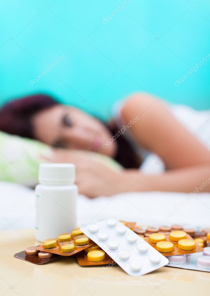 Sick woman in bed and pills from her medical treatment