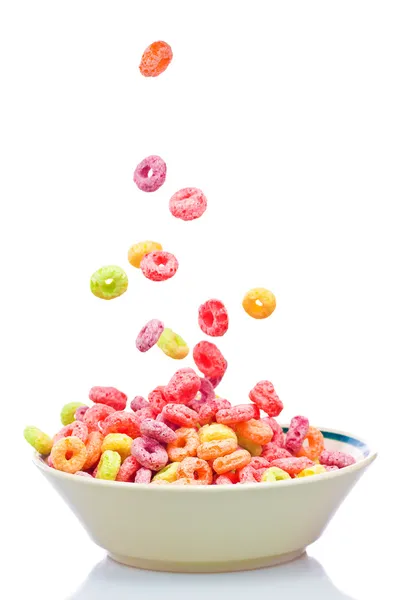 Cereales coloridos cayendo en un tazón aislado en blanco — Foto de Stock