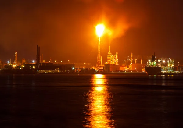 Нефтеперерабатывающий завод ночью с огромной кузницей, загрязняющей воздух — стоковое фото