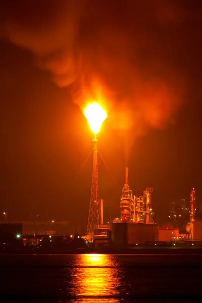 Ölraffinerie in der Nacht mit einer riesigen Schmiedesäule, die die Luft verschmutzt — Stockfoto