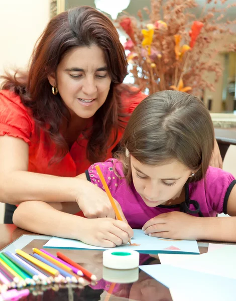 Молодая латинская мать помогает дочери с ее художественным проектом — стоковое фото