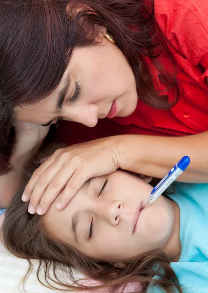 Hispanic mother checking the temperature of her sick little girl — Stock Photo, Image