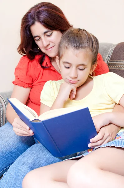 Latin flicka och hennes mamma som läser en bok hemma — Stockfoto