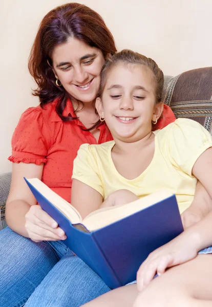 Menina latina e sua mãe lendo um livro em casa — Fotografia de Stock