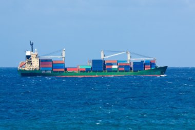 Cargo ship carrying containers on open sea clipart