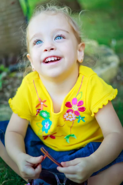 Hermosa niña pequeña sentada en un parque — Foto de Stock