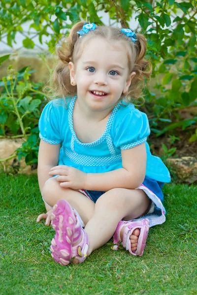 Menina loira pequena sentada em um parque — Fotografia de Stock