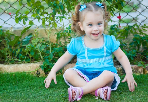 草の上に座って美しい小さなブロンドの女の子 — ストック写真