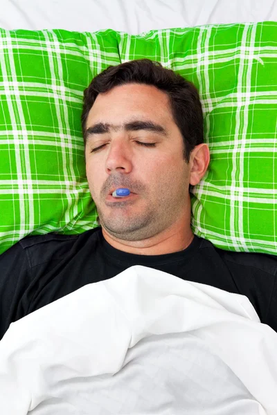 Хворий іспаномовний чоловік лежить у ліжку з термометром — стокове фото