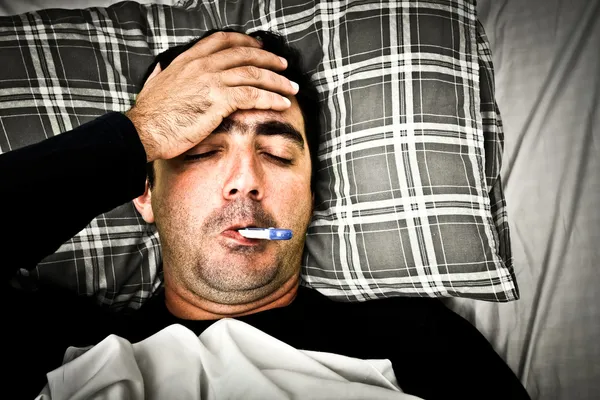Imagen dramática de un hombre enfermo en la cama con fiebre — Foto de Stock