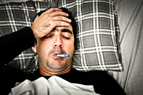 Dramatic image of a sick man in bed with fever