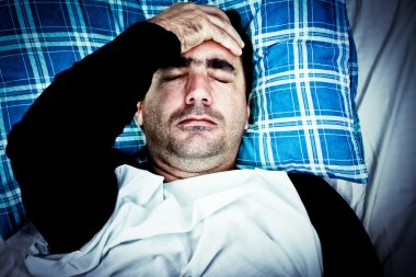 çok stresli adam yatakta döşeme bir baş ağrısı ile